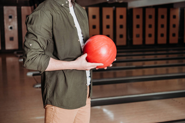 cropped shot of man holding bowling ball at club - Fotoğraf, Görsel