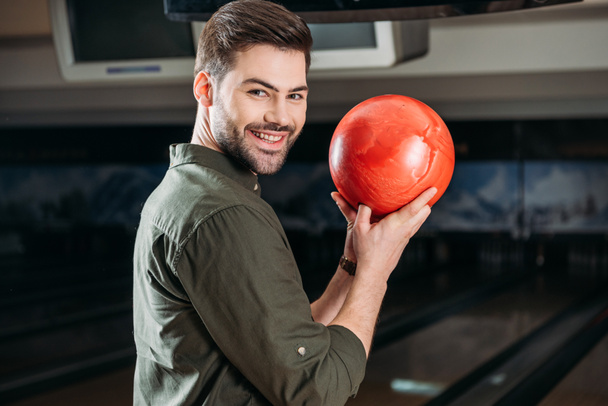 sorridente giovane uomo in possesso di palla da bowling e guardando la fotocamera
 - Foto, immagini