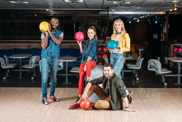 happy young friends posing with balls at bowling club - Foto, Imagem