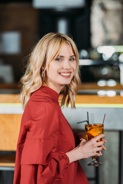 Gelukkig jonge vrouw met cocktail uitgaven tijd in bar - Foto, afbeelding