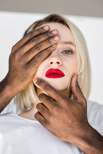 image recadrée de copain afro-américain touchant visage de petite amie blonde avec les mains
 - Photo, image