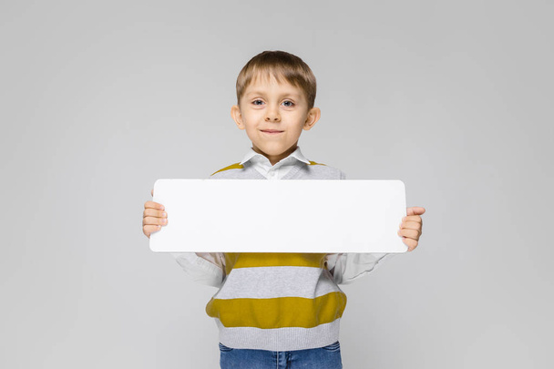 Portrait of adorable little boy holding empty plate on grey background - Foto, Imagen