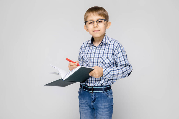 Portrait of adorable little boy in glasses holding book on grey background - Foto, Imagem