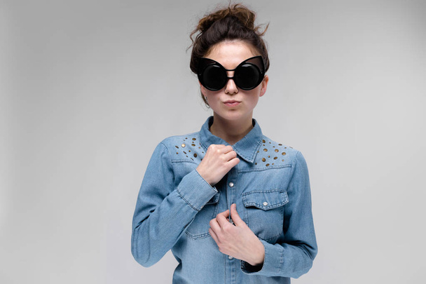 Gri izole güneş gözlüğü takıyor topuz saç modeli ile mutlu esmer beyaz kız - Fotoğraf, Görsel
