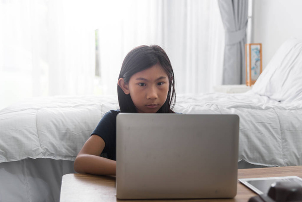Asian girl using laptop in bedroom with low light. - Photo, image