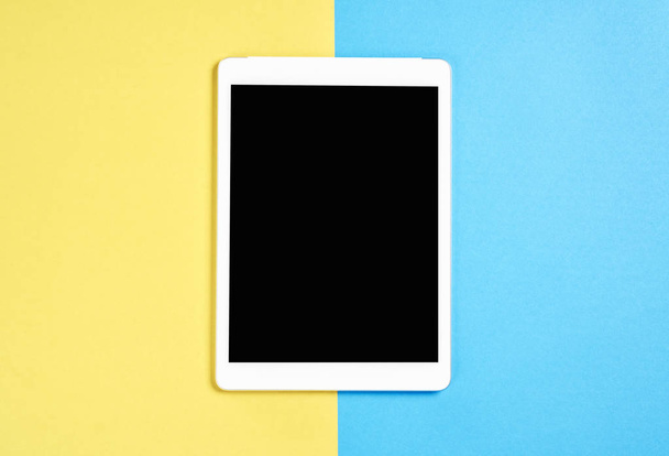 Top view; Modern workplace with tablet placed on a pastel yellow background. Copy space suitable for use in graphics. - Photo, Image