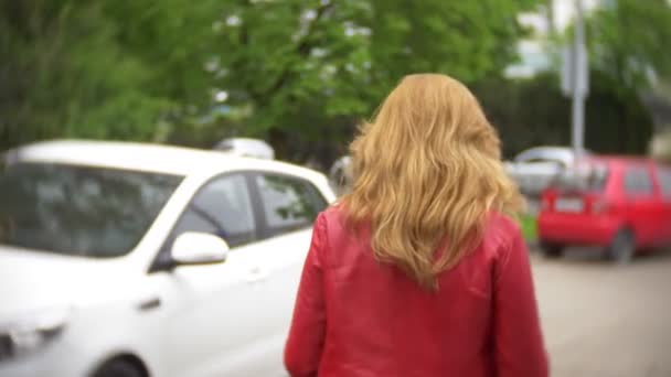 赤いジャケットの女性ドライバーは彼の車を駐車、道路の近くに近づくし、車で座る。4 k - 映像、動画