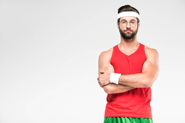 handsome sportsman posing in retro sportswear and sunglasses with crossed arms, isolated on white - Foto, imagen