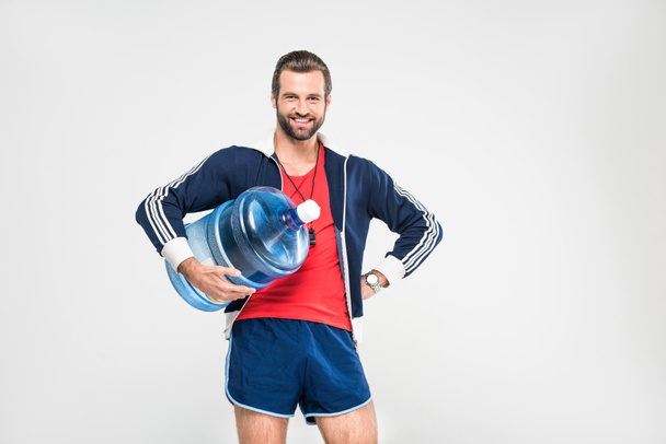 cheerful sportive coach holding big bottle of water, isolated on white  - Foto, imagen