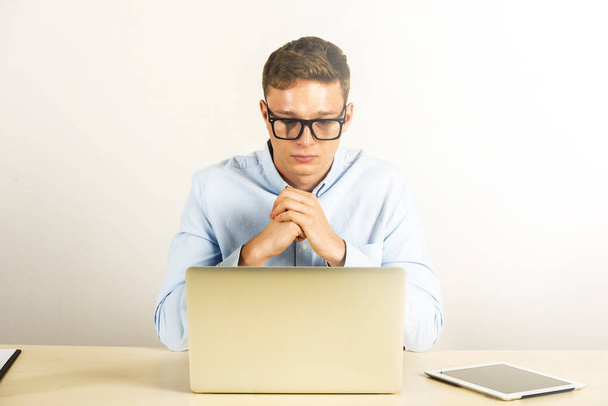 Νεαρός άνδρας που χρησιμοποιούν φορητό υπολογιστή στο γραφείο, το γραφείο, σκέψη πόζα. - Φωτογραφία, εικόνα
