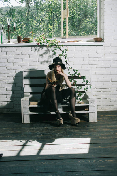 Fashion woman model read book. Poetry book at romantic writer. spring or summer girl relax on bench. Beauty and fashion look in vintage style. Pretty girl in black dress and retro hat - Photo, Image