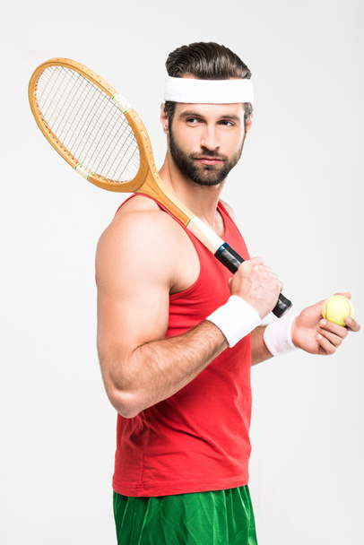 мышечный теннисист держит ретро деревянную ракетку и мяч, изолированный на белом
   - Фото, изображение