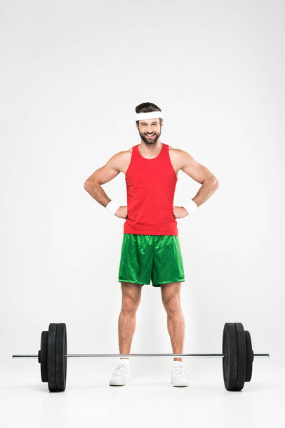 sportsman in retro sportswear standing near barbell, isolated on white - Photo, Image