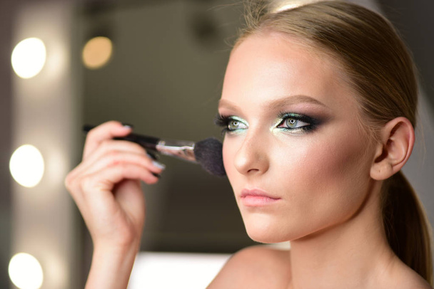 Glamour makeup for pretty woman in beauty salon. Glamour look with makeup brush. - Foto, Imagem
