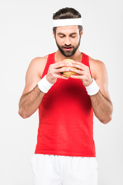 красивый спортсмен ест фаст-фуд, изолированный на белом
 - Фото, изображение