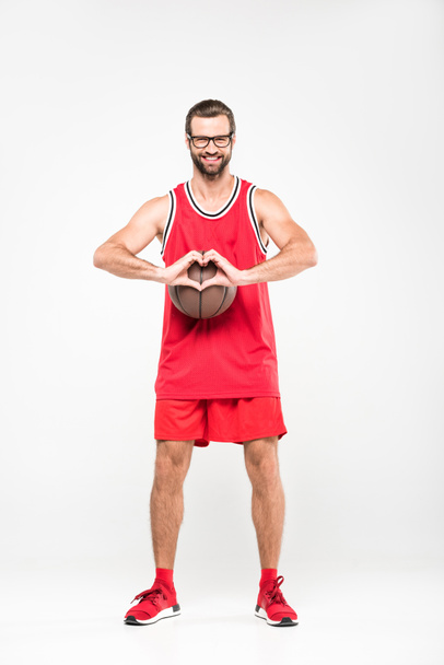 smiling basketball player with ball showing heart symbol, isolated on white - Foto, afbeelding