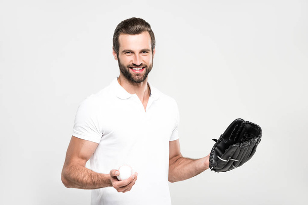 glimlachend bebaarde sportman met honkbal mitt en bal, geïsoleerde op grijs - Foto, afbeelding