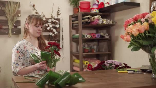Kwiaciarnia kobieta robi wystrój z kwiatami wielokolorowe ogród w sklepie - Materiał filmowy, wideo