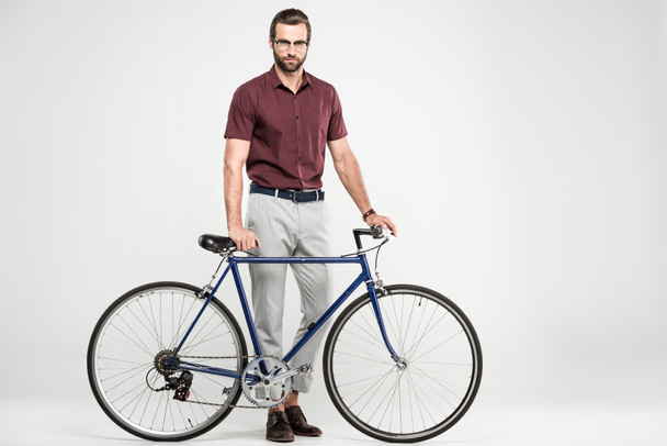 stylish man posing with bike, isolated on grey - Photo, Image