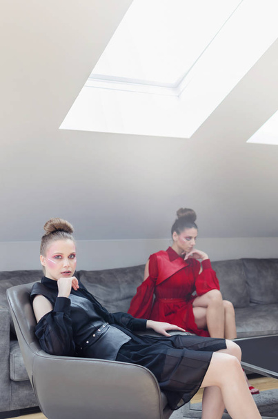 Two young models in designer clothes posing in luxury interior - 写真・画像