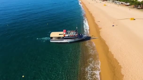 Vista aérea del barco en la playa de arena amarilla con gente en la costa en un día soleado y caluroso. España, Cataluña
 - Metraje, vídeo