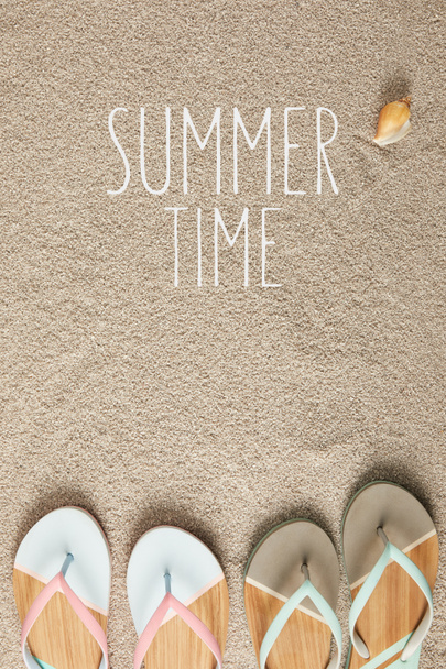 flat lay with summertime lettering, flip flops and seashell on sand - Photo, Image
