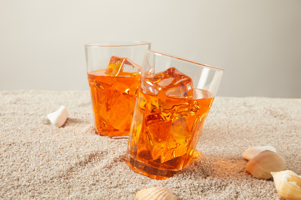 lähikuva lasit virkistävä cocktaileja hiekalla simpukoita harmaa bakgorund
 - Valokuva, kuva