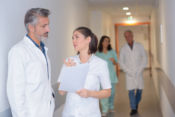 Nurse and doctor talking in hospital corridor - Фото, изображение