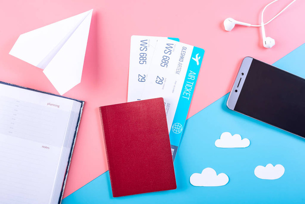 Flugtickets mit Reisepass und Papierflugzeug auf pastellfarbenem Hintergrund, Topview. das Konzept von Flugreisen und Urlaub - Foto, Bild