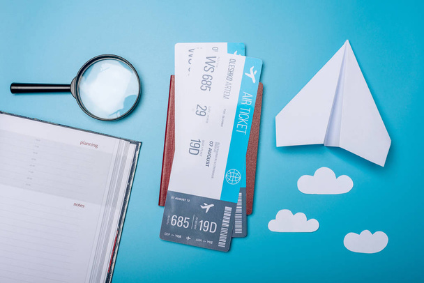 青色の背景、topview のパスポートと紙飛行機の航空券。空の旅と休日の概念 - 写真・画像