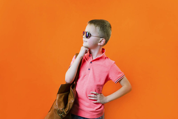 funny boy with a suitcase on a bright orange background travel - Fotografie, Obrázek
