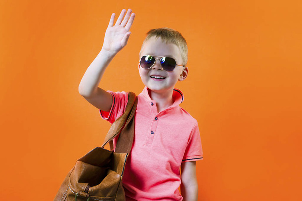 funny boy with a suitcase on a bright orange background travel - Zdjęcie, obraz