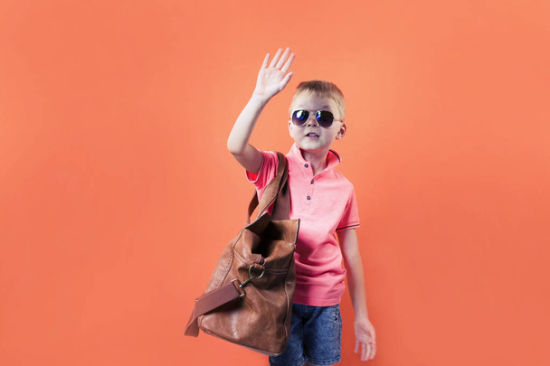 funny boy with a suitcase on a bright orange background travel - Fotó, kép