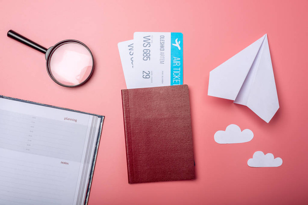 Авиабилеты с паспортом и бумажным самолетом на розовом фоне, вид сверху. Концепция авиаперелетов и праздников
 - Фото, изображение