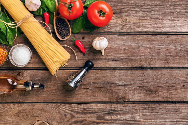 Pasta and ingredients on wooden background with copy space. Top view. Vegetarian food, healthy or cooking concept. - Photo, Image