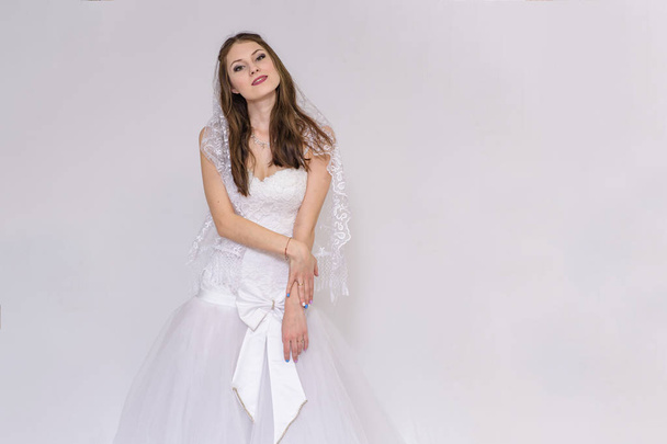 beautiful bride in white wedding dress in different poses on white backgrounds shows different emotions - Fotó, kép