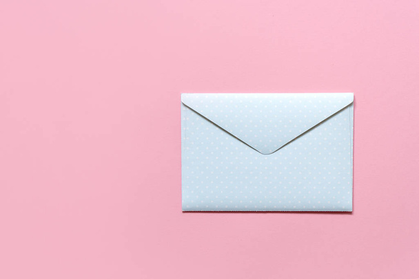 envelope azul em ervilhas brancas sobre um fundo rosa
 - Foto, Imagem