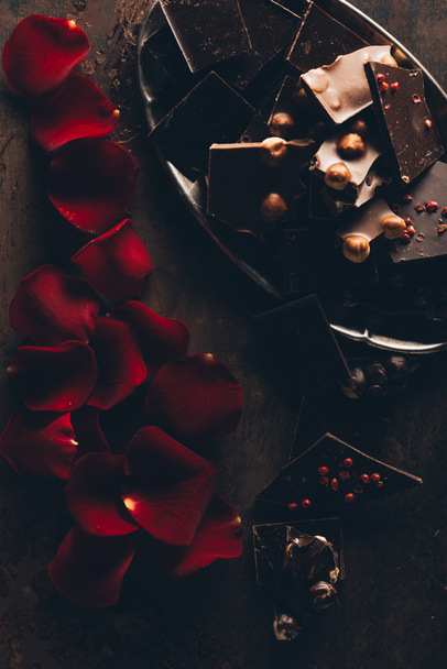 vista superior de hermosos pétalos de rosa roja y trozos de chocolate gourmet con nueces
  - Foto, imagen