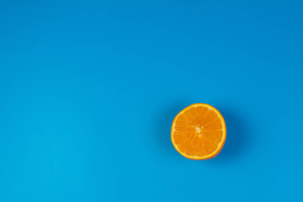 Orange mûr coupé en deux sur fond bleu, vue de dessus
 - Photo, image