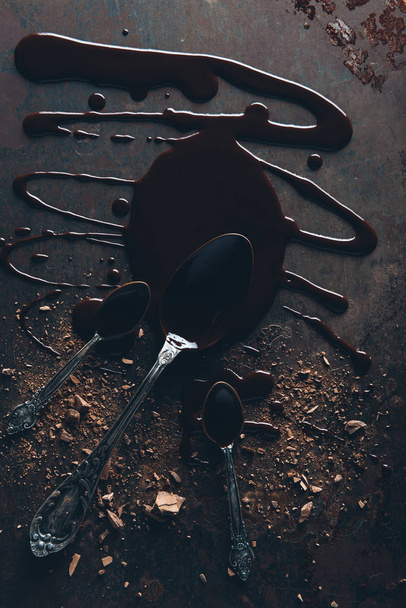 Widok z góry z rocznika łyżki i pyszne rozpuszczoną czekoladę na ciemnej powierzchni - Zdjęcie, obraz