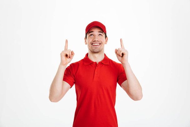 Happy young delivery man pointing isolated - Fotoğraf, Görsel