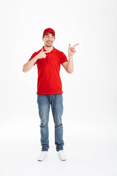 Full length image of young courier in red uniform presenting cop - Fotoğraf, Görsel