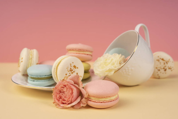 Multicolored macaroons cake are placed in a saucer and a cup alo - Zdjęcie, obraz