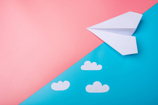 Fehér papír origami repülőgép felhők fekszik pasztell kék háttér - Fotó, kép
