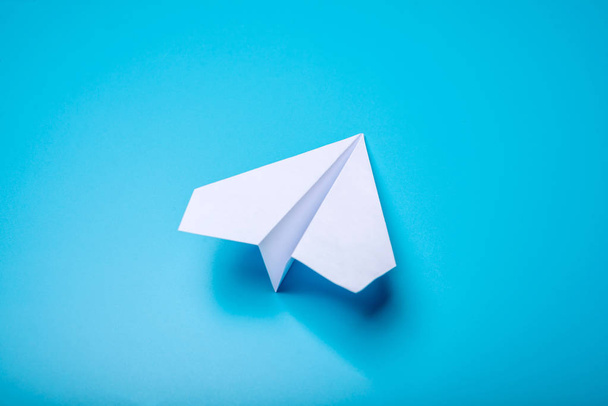 パステル ブルーの背景にあるホワイト ペーパー折り紙飛行機 - 写真・画像