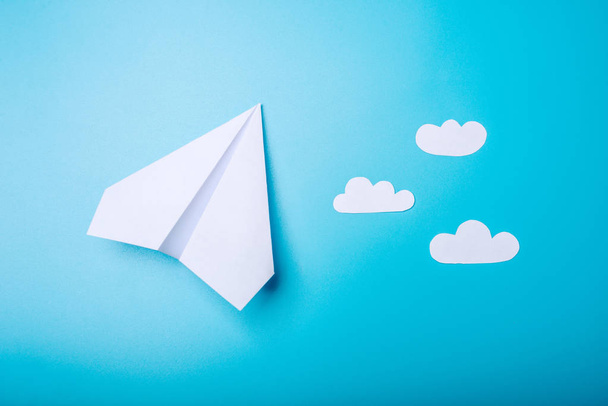 White paper origami vliegtuig ligt op pastel blauwe achtergrond - Foto, afbeelding