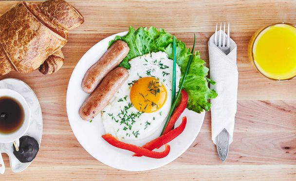 Νόστιμο πρωινό στο Λευκό πιάτο που αποτελείται από αυγό λουκάνικα vegatables τσαγιού χυμό πορτοκαλιού. Το Top view - Φωτογραφία, εικόνα