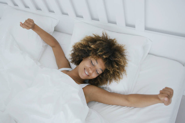 Content woman awakening in bed - Zdjęcie, obraz