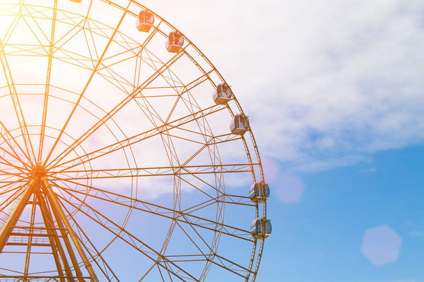 Ferris wheel against the blue sky and white clouds in the sun - Photo, Image
