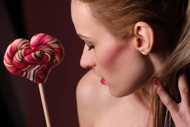 emotional sexy girl with a lollipop over pink background in studio - Fotoğraf, Görsel